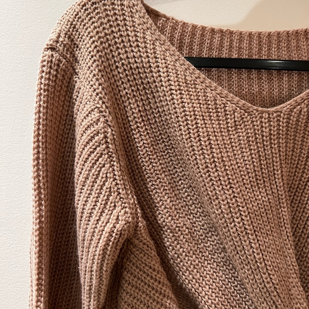 Pink sweater with know detail on front.